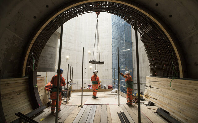 Three works inside a giant new sewer watching a crane