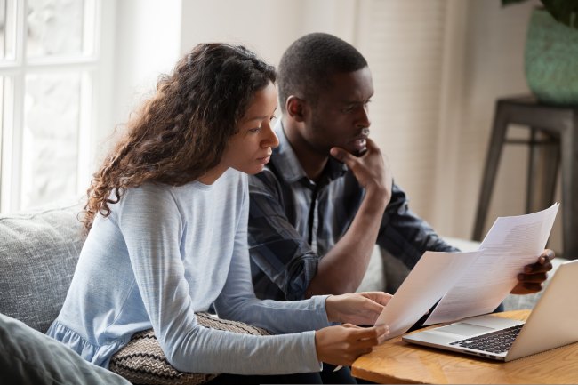 A man and woman looking at documents on a sofa