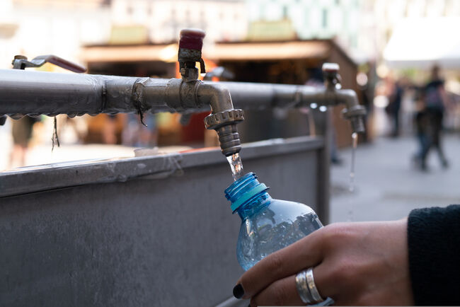 A public water tap being used to fill a bottle